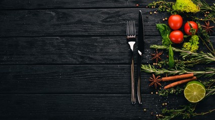 The background of cooking. Cutlery and vegetables on a wooden surface. Top view. Free space for...