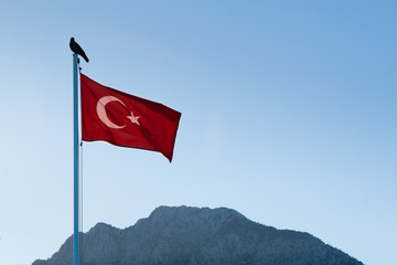 Turkish flag on the flagpole fluttering from the wind. Mountains