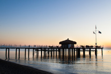 Obraz premium The bungalow on the pier is flooded with sunlight. Blue from the dawn sky.