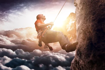 Tuinposter Alpinisme Man wearing shirt using rope to climb steep cliff