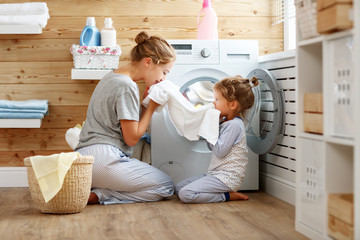 Happy family mother housewife and child   in laundry with washing machine - obrazy, fototapety, plakaty