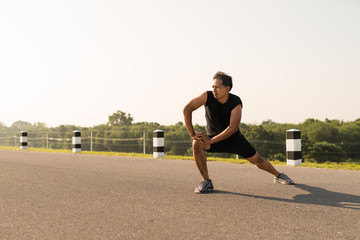 Male runners are stretching the leg muscles to prepare for a run in the morning. The concept of health and fitness