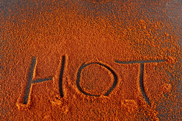 Top view on the texture background of red chilli pepper powder with text isolated on dark background