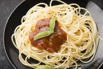 Spaghetti bolognese in black plate on vintage table background,Spaghetti with Spicy Mixed sauce and meat