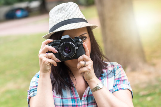 Beautiful young woman taking pictures in a park, light effect