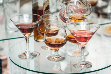different alcohol drinks on a glass stand. wine, champagne, cognac, vodka, martini