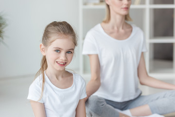 Obraz na płótnie Canvas happy little child practicing yoga with mother
