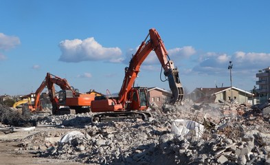 Fototapeta na wymiar Excavators at work in the ruins of a demolished building for urban redevelopment