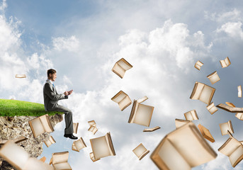 Man using smarphone and many books flying in air