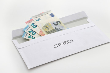 Briefumschlag mit diversen Euroscheinen und der Aufschrift sparen