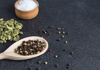 Green cardamom pods and mix peppers balls in wooden spoon