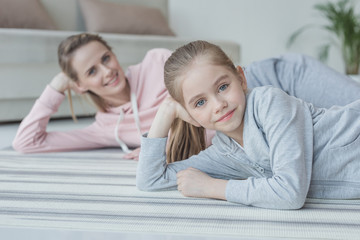 mother and daughter looking at camera while lying on floor