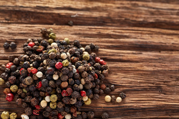 Top view on black, red and white peppercorns isolated on wooden background, shallow depth of field.
