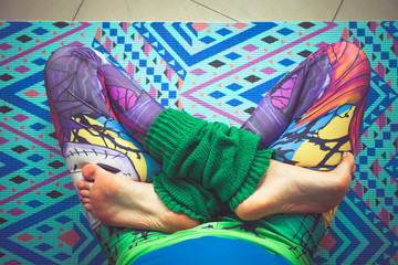 woman legs in colorful leggings in lotus pose from above view indoor