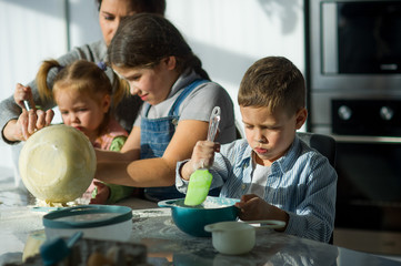 Fototapeta premium Mother and three children prepare something from the dough.