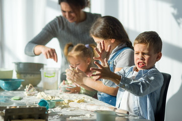 Mother and three children prepare something from the dough.