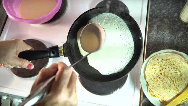 the cook pours the dough to make a pancake in a frying pan