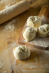 Handgemachte Tortelloni auf Holzbrett mit Mehl und Nudelholz