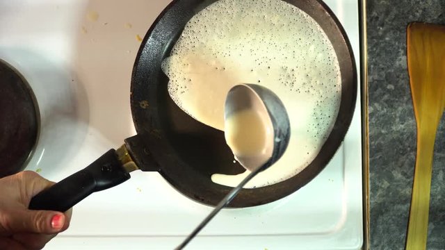 the cook pours the dough to make a pancake in a frying pan