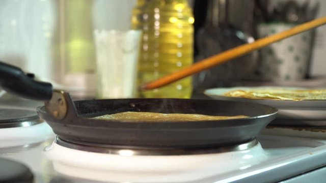 The chef takes a pancake in a frying pan and puts it in another plate