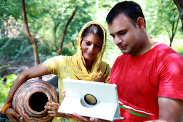Men & women of Indian ethnicity standing in stable of buffalo and using digital tablet outdoor nature.  
