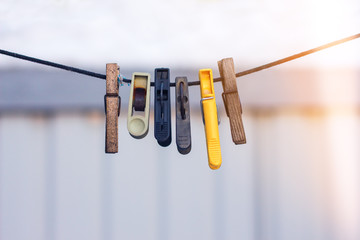 old clothespins on a rope hanging outside house; light glare from right; winter time