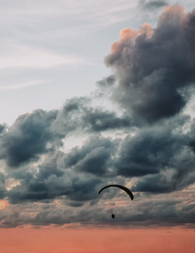Person paragliding in sunset