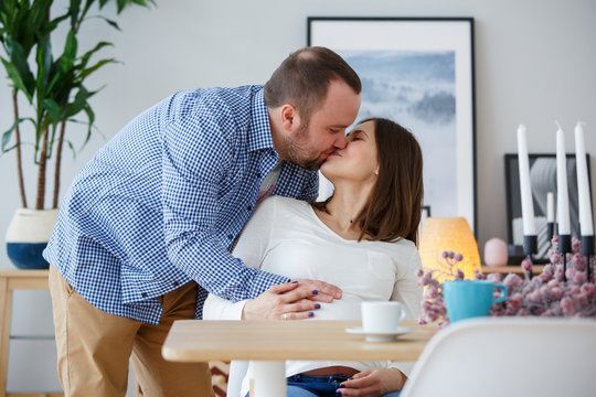 Photo of happy husband kissing pregnant wife