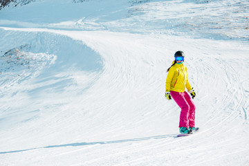 Fototapeta na wymiar Photo of sports girl in helmet riding snowboard from mountain slope