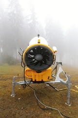 Yellow snow cannon from behind by foggy forest