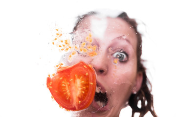 Kaputte Tomate auf Fensterscheibe, Frau mit Grimasse dahinter
