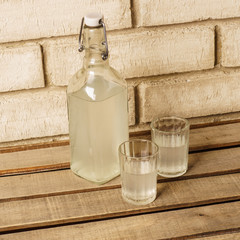 The bottle of vodka and two shot glasses outdoor. Bottle and sho