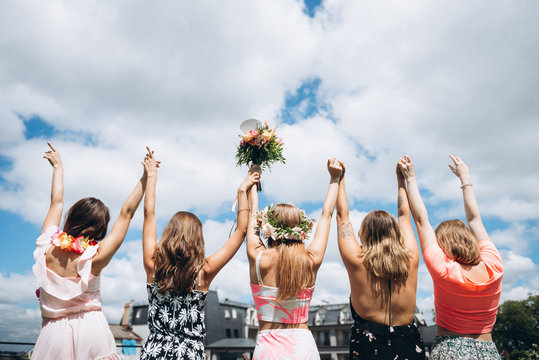 Girls raised their hands up on cloudy sky background at hawaii style hen party