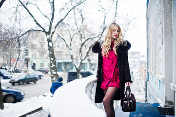 Obraz na płótnie Canvas Elegance blonde girl in red evening dress and fur coat at streets of city in winter day.