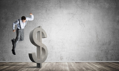 Determined banker man in empty concrete room breaking dollar figure