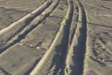 Footprints in the snow at sunny day, the setting sun and shadows on the snow.