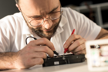 man using multimeter while testing hard disk drive