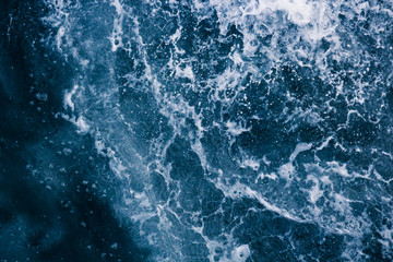 Fototapeta na wymiar The surface of the sea with waves, splash, foam and bubbles, blue abstract background