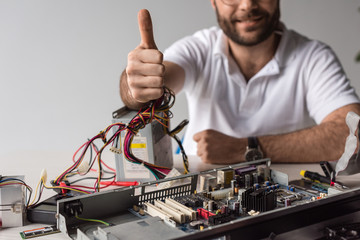man showing thumb up against broken computer