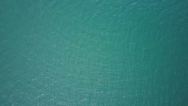 A birds eye view shot of a blue ocean. Camera moves forward