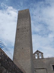 Fototapeta premium Mole medievale con uccelli in volo mura e cappella con campane
