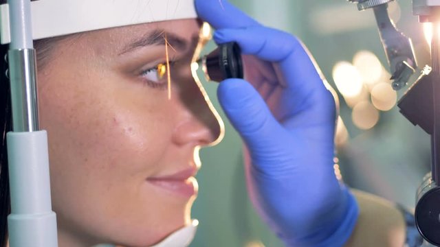Close up of an ocular in doctor's hands being used for young woman's eyes check up