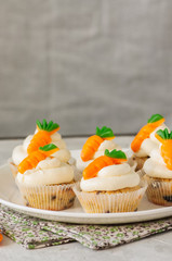Vanilla cupcakes with chocolate chips and cream cheese frosting decorated with carrot marmalade.