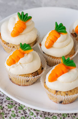 Vanilla cupcakes with chocolate chips and cream cheese frosting decorated with carrot marmalade.