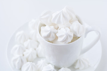 The white merengue in the white tea cup on white background, top view