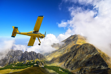 Old and vintage cessna plane flying above Carpathian mountain peaks in Romania - obrazy, fototapety, plakaty