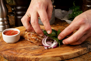 Closeup of chef's hands decorating meat steak with basil leaves.