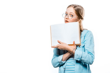 teenage girl in eyeglasses holding blank book and looking at camera isolated on white