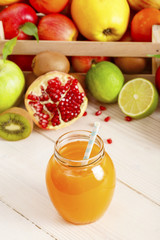 A glass of juice with a straw from different fruits