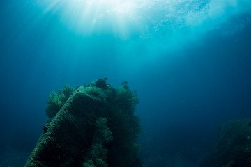 Underwater seascape with natural sunlight through water surface and rocks on the seabed.underwater background